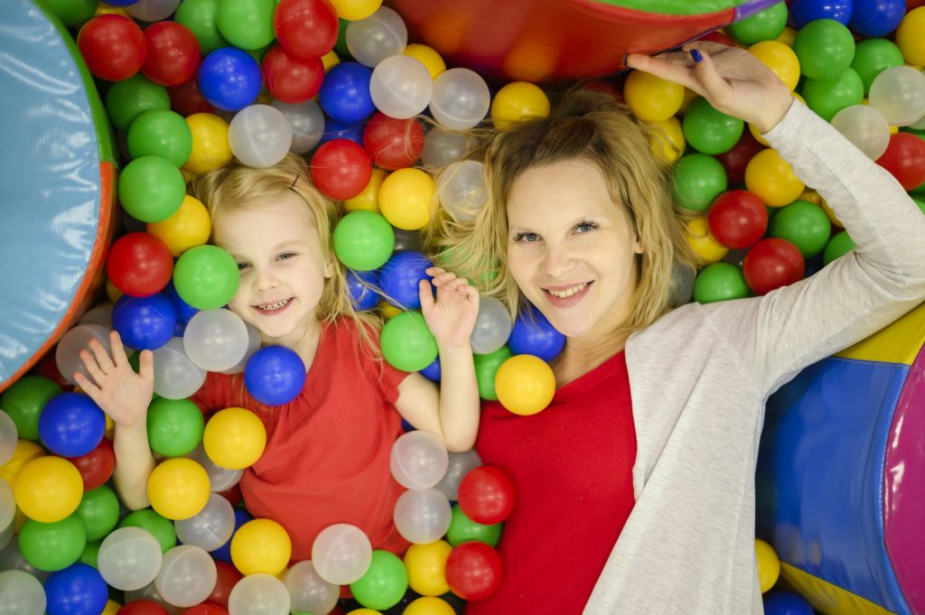 Niña y madre disfrutando en parque de bolas